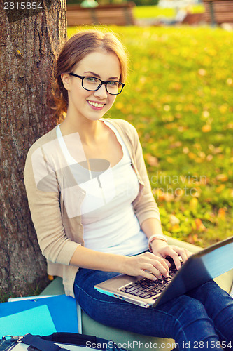 Image of smiling teenager in eyeglasses with laptop