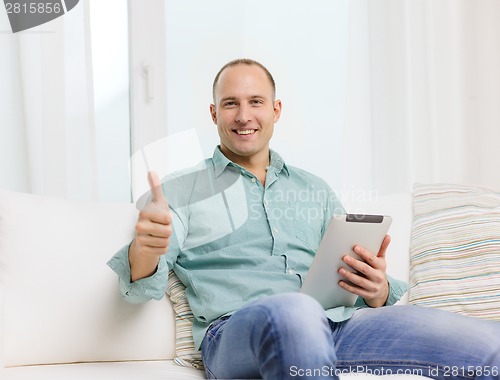 Image of smiling man working with tablet pc at home