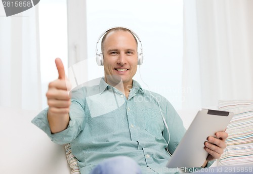 Image of smiling man with tablet pc and headphones at home