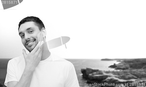 Image of beautiful smiling man touching his face