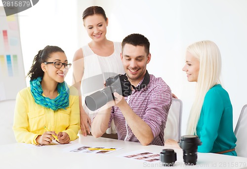 Image of smiling team with photocamera working in office