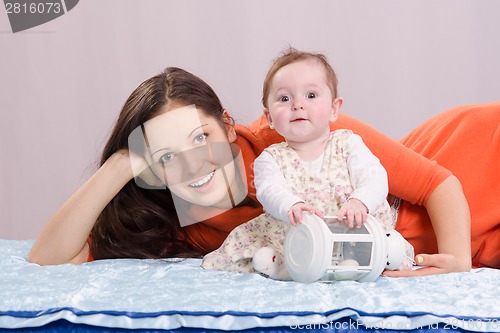 Image of Mom with a six-month daughter playing on the bed