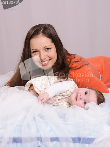 Image of Mom and baby lying on the bed having fun