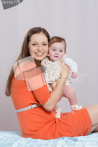 Image of Mom with a six-month daughter sitting on bed
