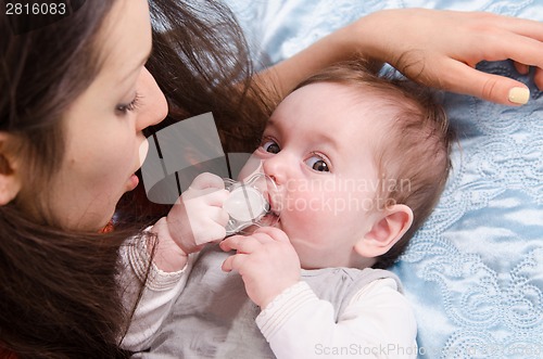 Image of Mother playing with her daughter in crib