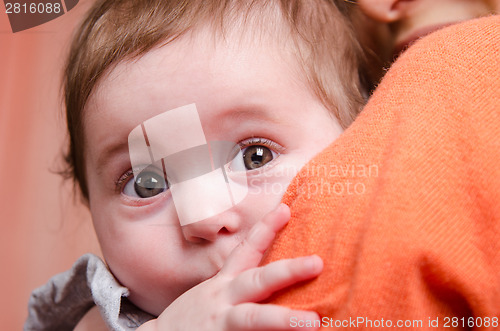 Image of Scared kid hiding behind mom's shoulder