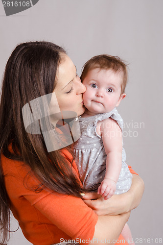 Image of Young happy mother kissing her daughter