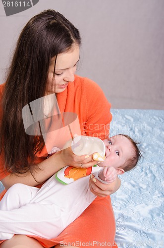 Image of Young mother feeding bottle six-month baby girl