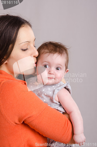 Image of Happy mother kissing her daughter six-month