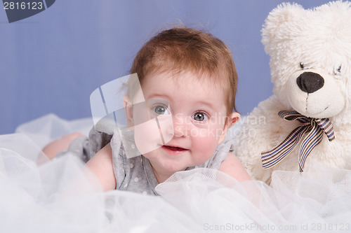 Image of Six-month baby girl with teddy bear on sofa