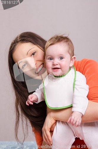 Image of Young happy mother hugging baby girl in bib