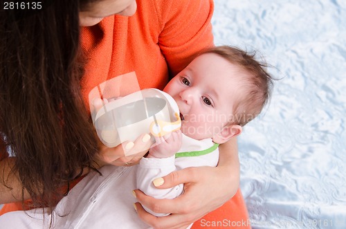 Image of Mum feeds from a bottle six-month baby girl
