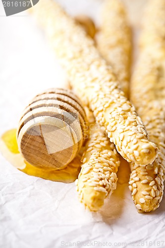 Image of grissini with sesame seeds and honey dipper