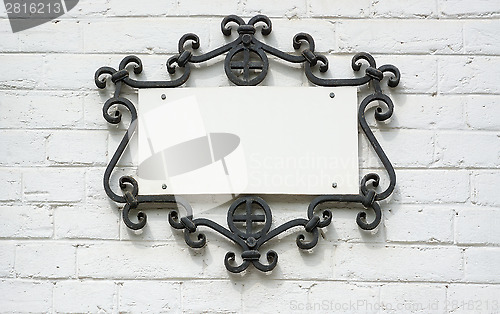 Image of Information plate in forged frame on a brick wall.