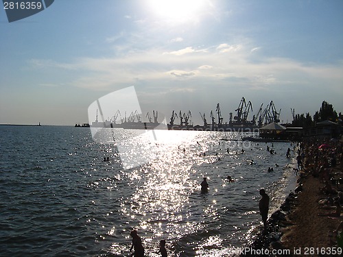 Image of evening sea with hoisting crane in the seaport