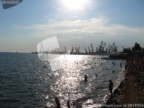 Image of evening sea with hoisting crane in the seaport