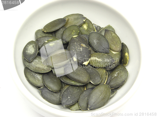 Image of Pumpkin seeds in bowl of chinaware on white background