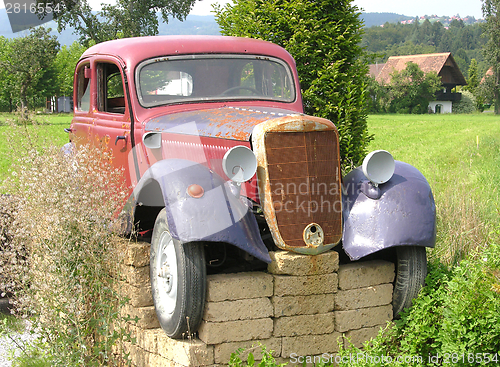 Image of Rusted veteran car jacked up in the open countryside
