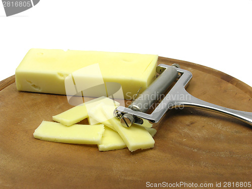 Image of Hard cheese on wooden plate with cheese slicer