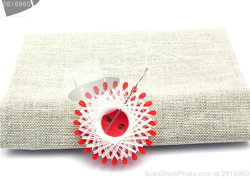 Image of White thread with sewing needle on linon