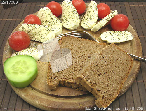 Image of Sliced mozzarella with little tomatoes, a slice of cucumber and