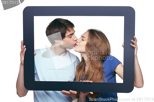 Image of In love couple holding tablet frame kissing