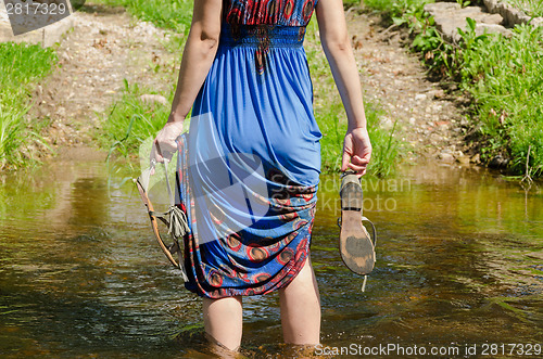 Image of girl holds sandals wade barefoot flowing stream 
