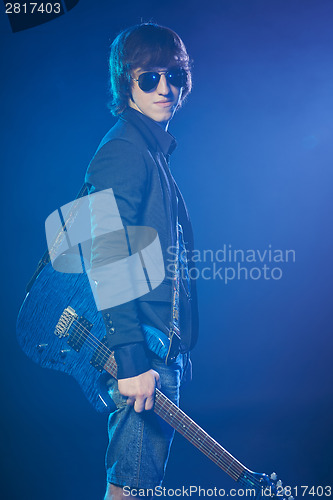Image of Young guitarist standing in smoke on stage