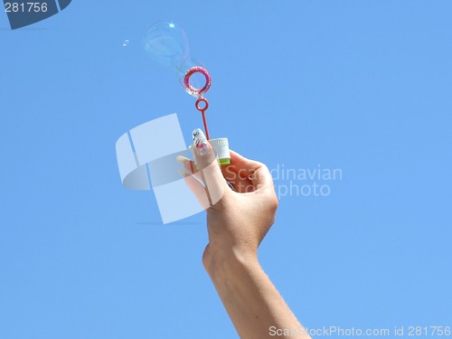 Image of Female hand and soap bubbles on a background of the blue sky