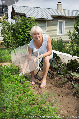 Image of Mature woman sitting on a chair of his garden