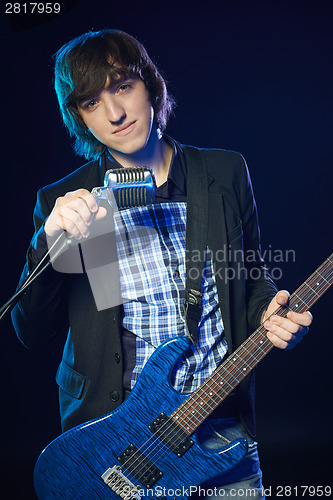 Image of Young guitarist standing in smoke on stage