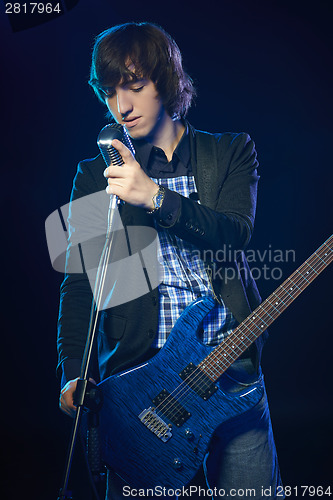 Image of Young guitarist standing in smoke on stage