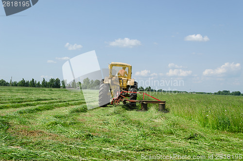 Image of tractor make sharp turn and leaves cut grass tufts 