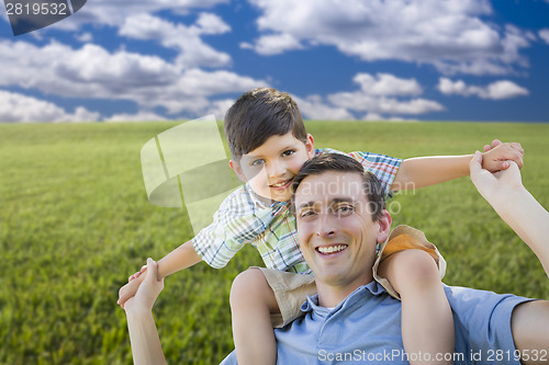 Image of Mixed Race Father and Son Playing Piggyback on Grass Field