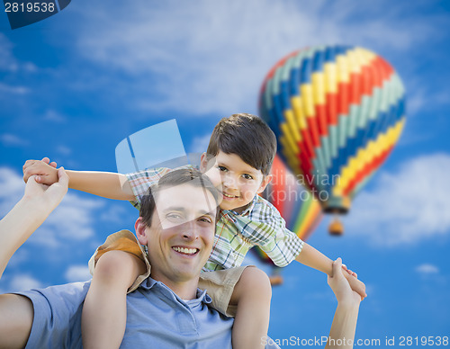 Image of Father and Son Playing Piggyback with Hot Air Balloons Behind