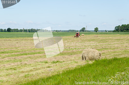 Image of Dry haystack roll and blur tractor ted hay field 