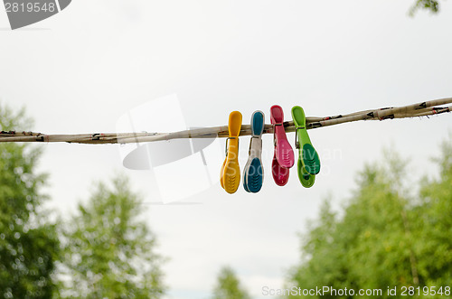 Image of colorful clothes pins hanging on rope outdoor 