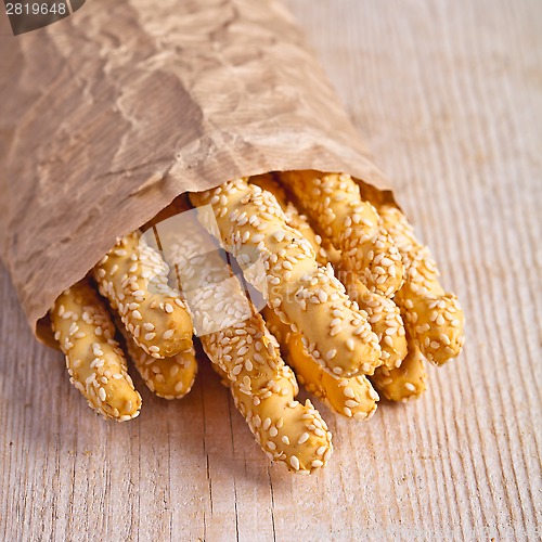 Image of bread sticks grissini with sesame seeds in craft pack 