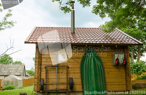 Image of household utensil and boat hang on bathhouse wall  