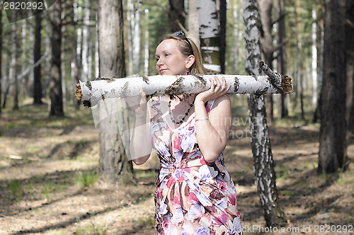 Image of The young woman with a log in the wood.