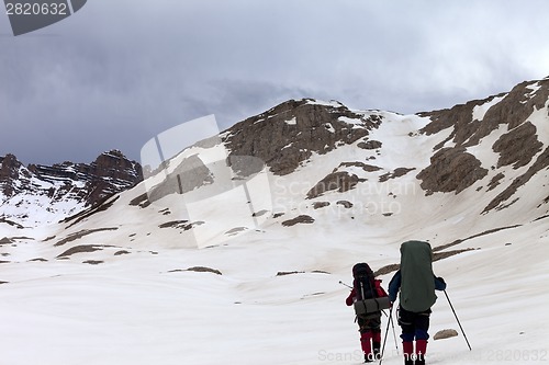Image of Two hikers on snowy plateau before storm