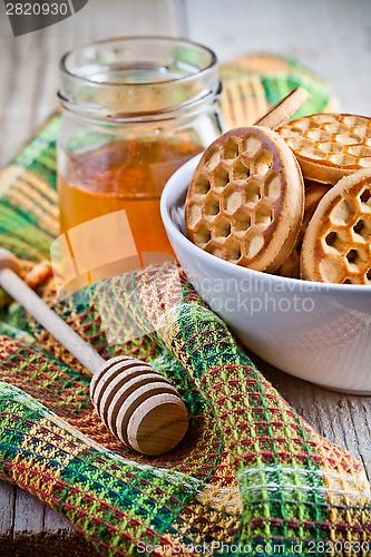 Image of fresh cookies in a bowl, tablecloth and honey 
