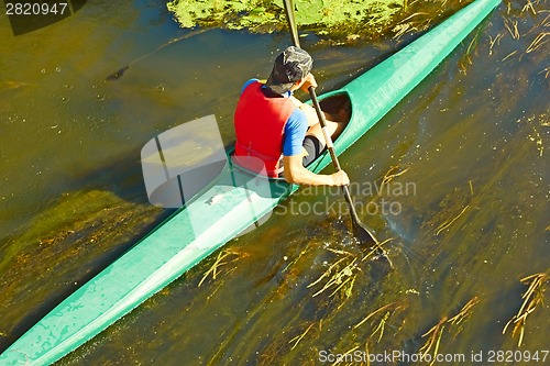 Image of Canoeist floating on the overgrown river 