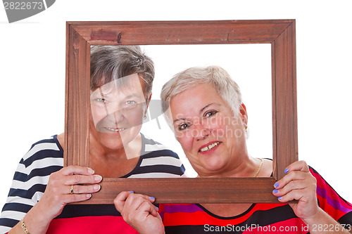 Image of Two senior women looking through a picture frame