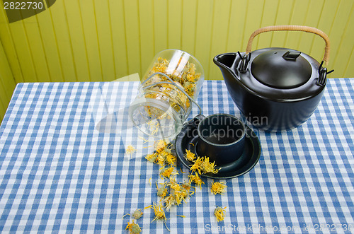 Image of jar dried coltsfoot on table black ceramic tea pot 