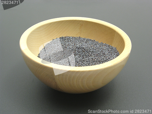 Image of Wooden bowl with poppy seeds on a dull matting
