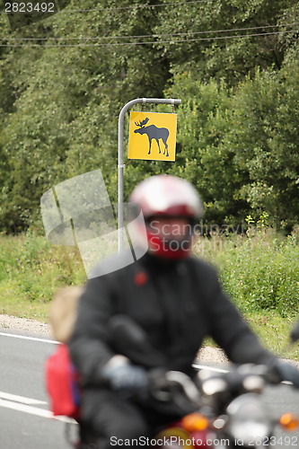 Image of motorcyclist on a background road sign