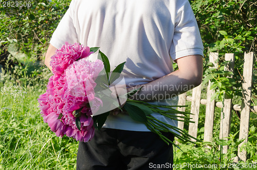 Image of close up of man back with peony in hand 