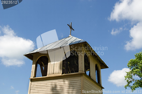 Image of wooden village bell tower on blue sky background 