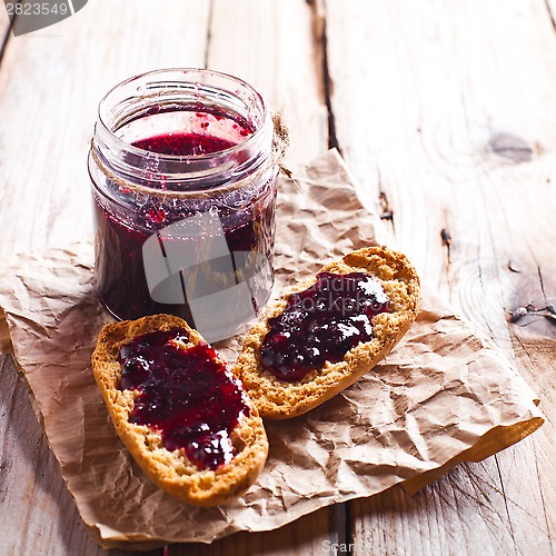 Image of black currant jam in glass jar and crackers